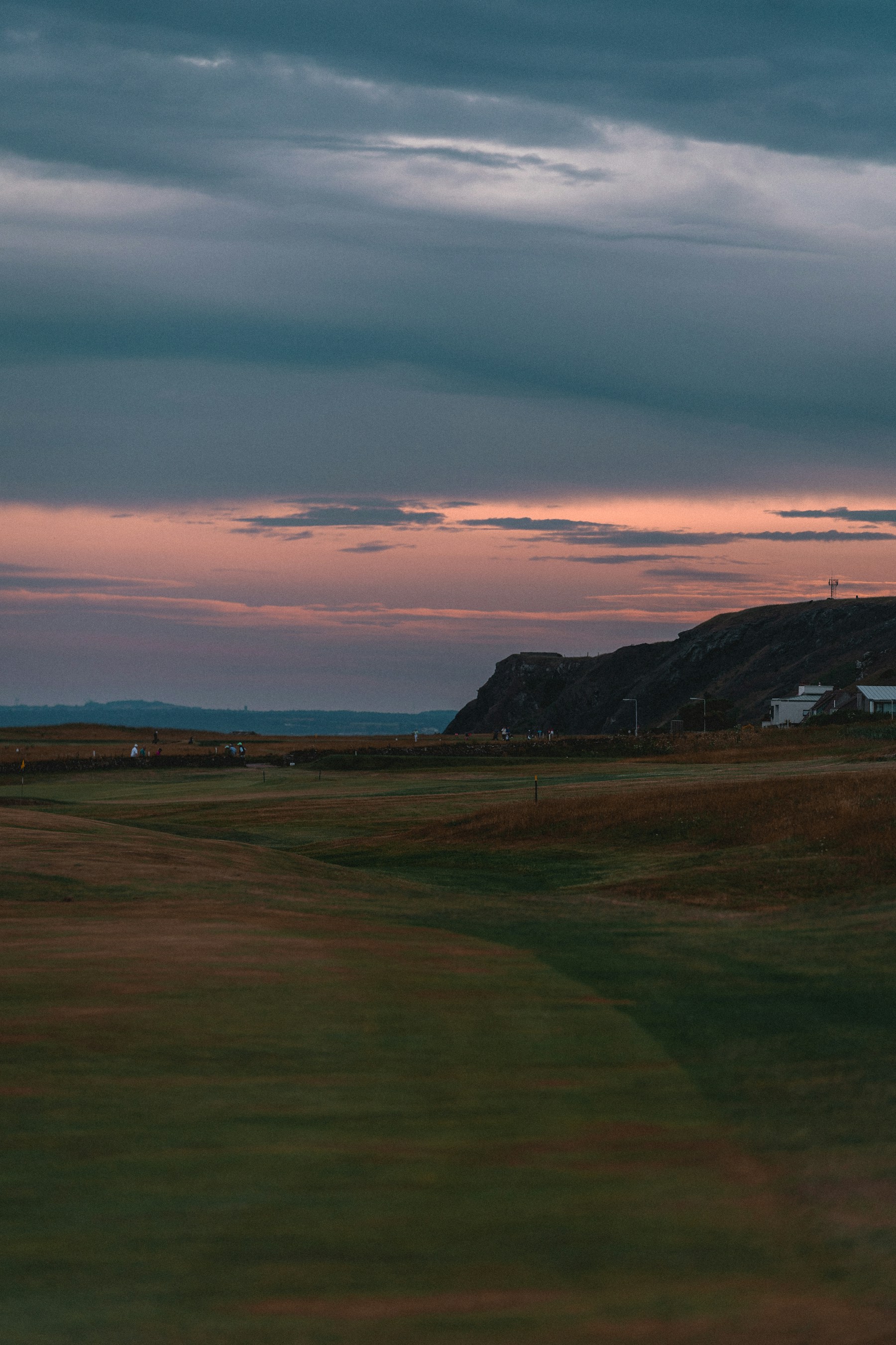 A links golf course at dusk, moody sky over the coast