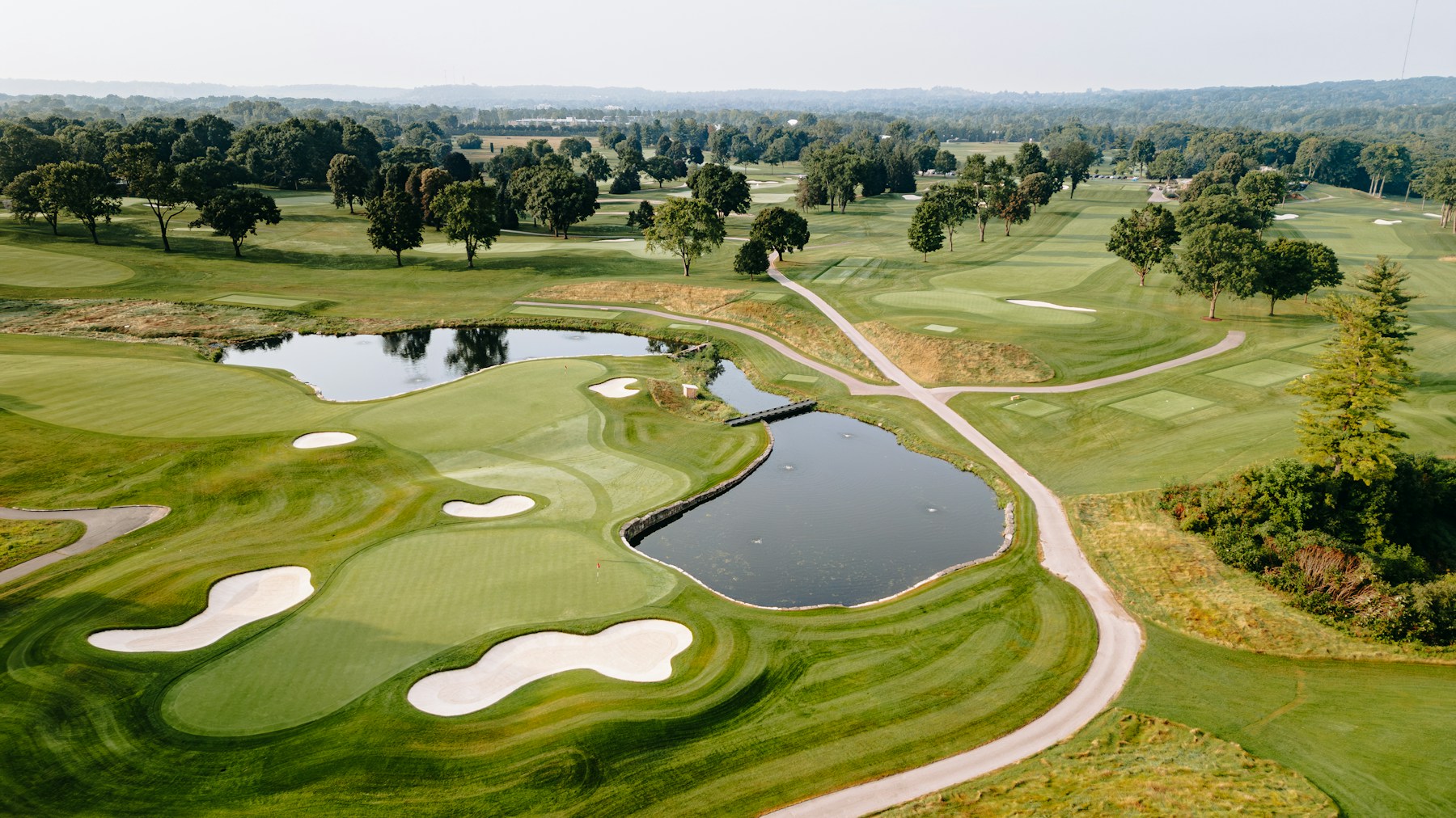 An aerial view of a golf green with bunkers and a water hazard