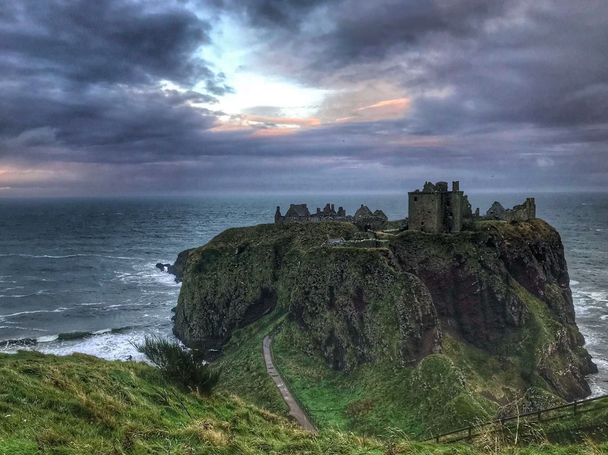 A dramatic landscape with a castle on the mountainside
